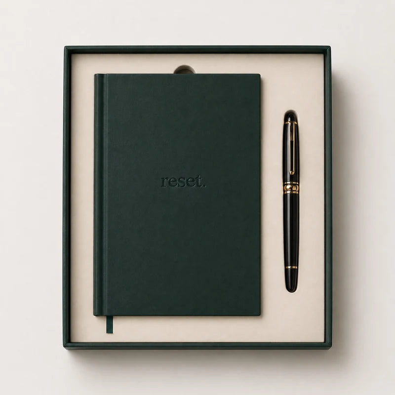 Forest-green reset. journal in its presentation box beside a pen